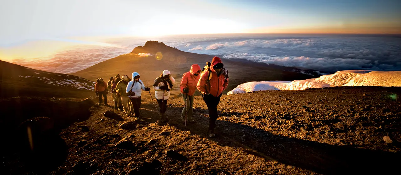 Climbers hiking Kilimanjaro summit trail at sunrise